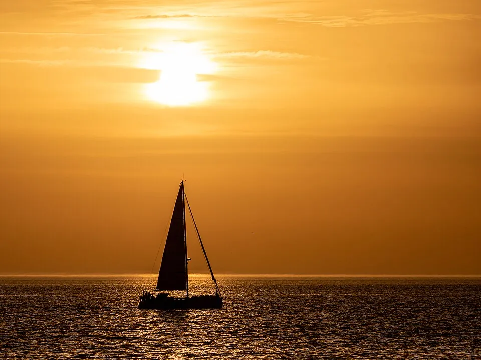 夕日の海に浮かぶ帆船